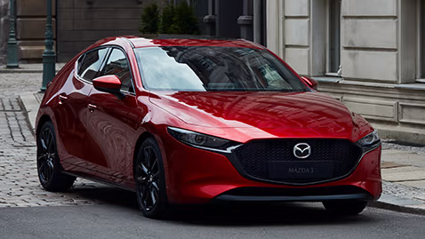 Red Mazda hatchback car parked on a street.